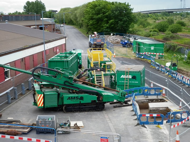 The AMS No-Dig Powerbore 70 tonne drill rig set up on site. The mud recycling system can also be seen behind the drilling rig